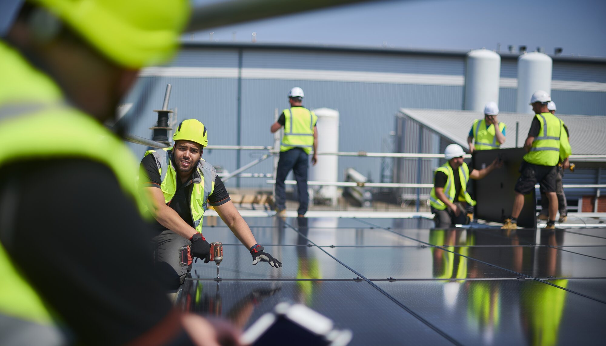 Team of workers in hi-vis vests and hard hats installing solar panels on a commercial site
