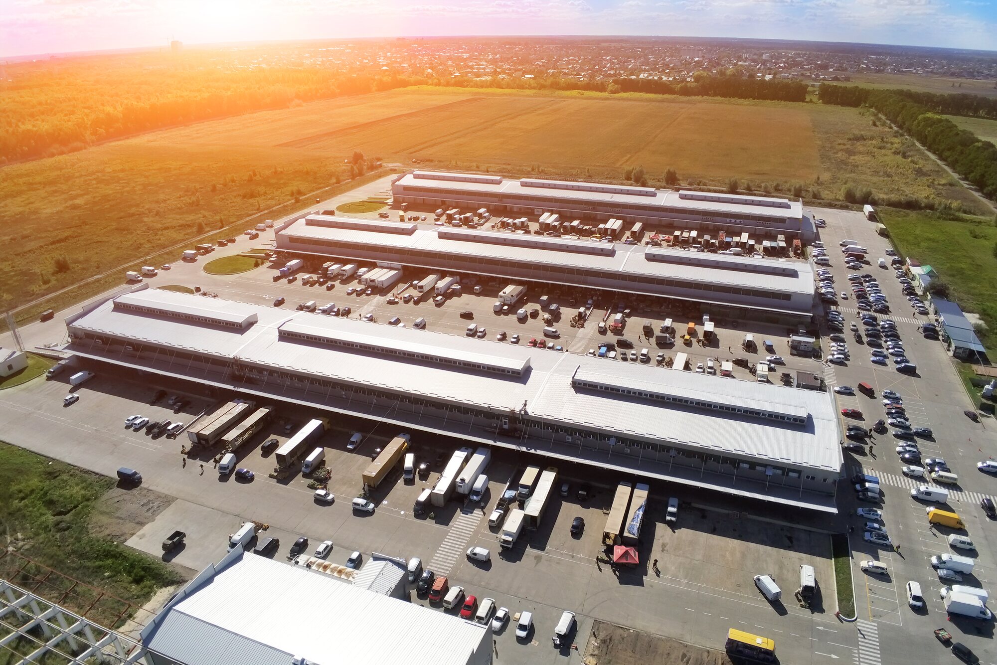 Aerial drone view of a large distribution warehouse with loading bays and lorries